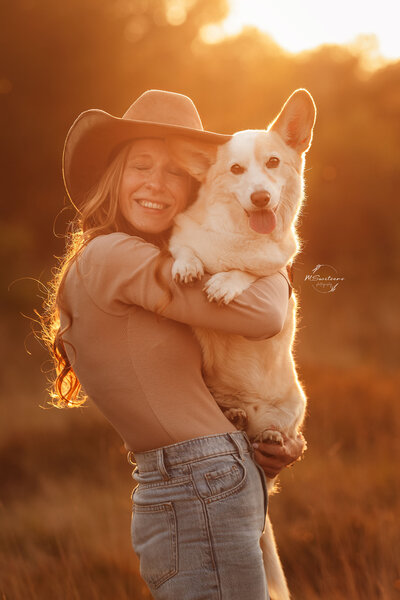 Fotoshoot tijdens golden hour met baasje en corgihond op buitenlocatie bewerkt in een warme sfeer. 