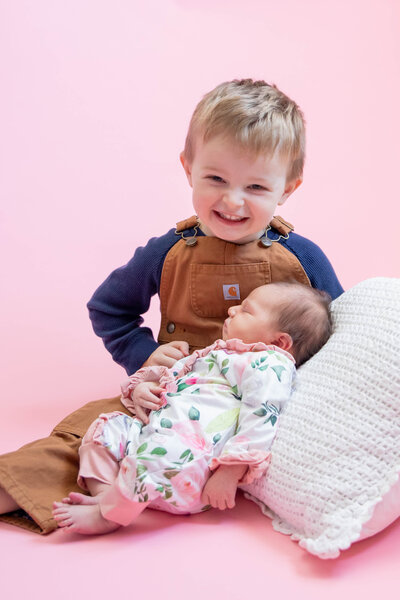 Brother and baby sister with pink background | Newborn Session Photographer
