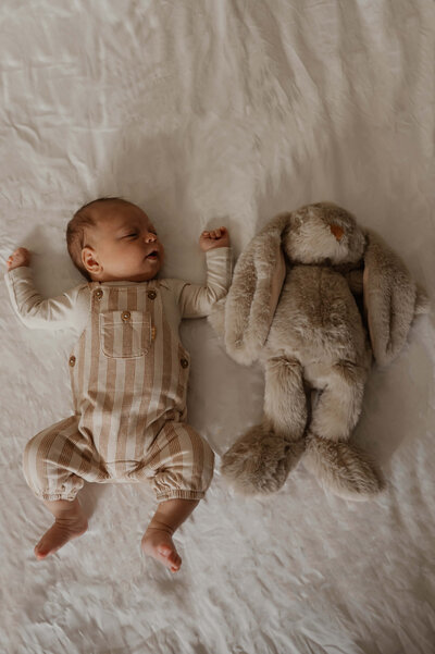 Baby ligt op bed met zijn lieveling knuffel.