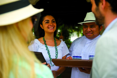 People in white welcome guests with refreshing beverages upon their arrival