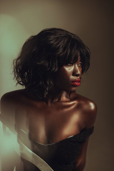 Women wearing a black top, red lip stick, brown curly hair, neutral brown background