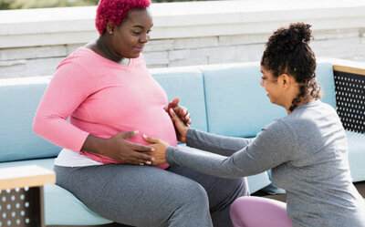 A female doula massaging the belly of pregnant woman