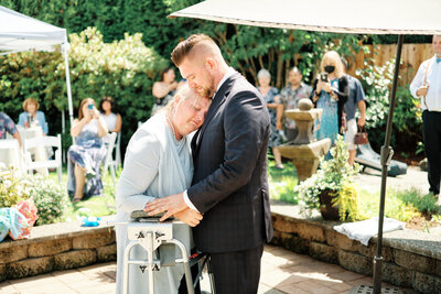 Bride rubs sunscreen onto the grooms face as a wedding toast occurs in the background