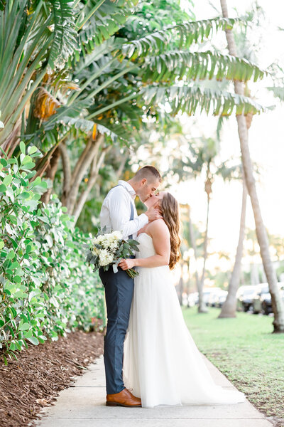 couple kissing on a path of trees by naples fl wedding photographer