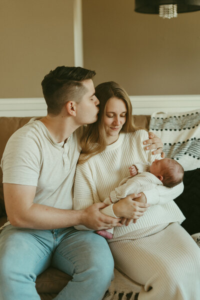 newborn lifestyle photo of a mom and dad holding baby  in a cabin with a cat