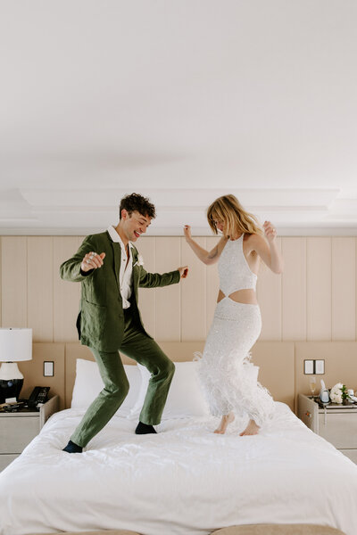 A newlywed couple jumping on a bed together 