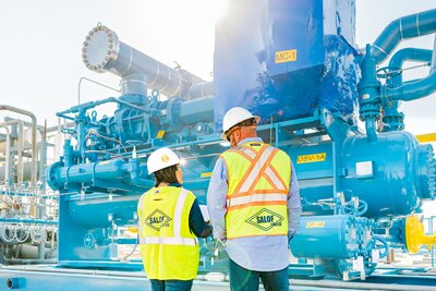 Branding session at manufacturing site in Texas with two employees in safety vests reviewing a blue vessel.