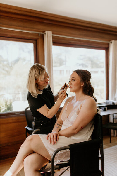Bridal makeup artist Yana applying lipstick to client in her San Francisco beauty studio.
