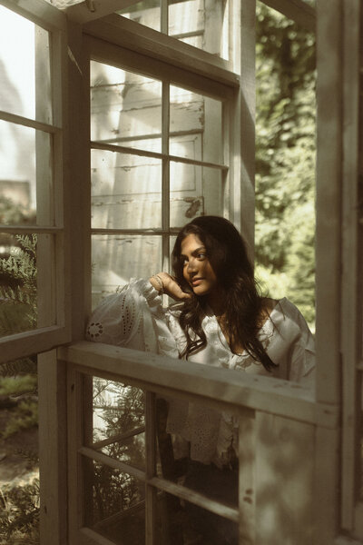 A senior girl leaning against the window pane at Das Hinter Haus Studio in Atlanta, Ga. 