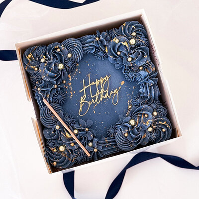 Blue buttercream square sheet cake splashed with gold with Happy Birthday in gold on the top with a gold candle