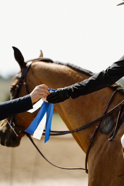 a rider being handed a blue ribbon after their course at a Trillium show in Ontario captured by a private client photographer