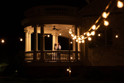 A newlywed couple dancing in a gazebo at night 
