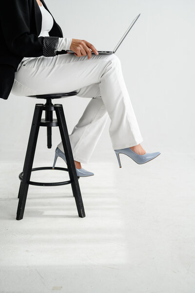 A personal branding photographer in denver captures a photo of a woman sitting on the kitchen counter holding up wine and celebrating during her personal brand photo shoot and branding photos for business.