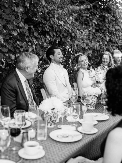 Bride and groom laughing at speeches at their garden welcome dinner at Salamander Resort.