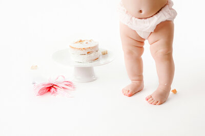 Baby feet and simple white cake for first birthday cake smash with fresno baby photographer