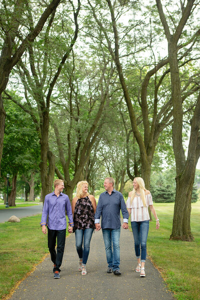 family of four holding hands walking down a paved path