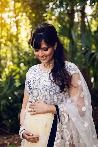 A stunning Indian pregnant women in a blue and yellow sari, showcasing elegance during a maternity photoshoot.