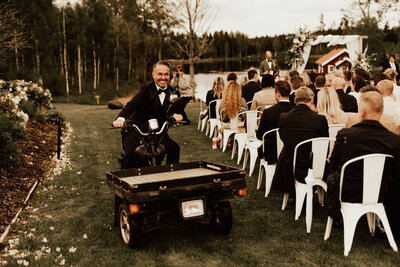 groom rides on a motor bike to the outdoor ceremony