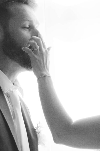 Close-up of groom with bride's arm playfully putting cake icing on his nose, captured during their wedding celebration