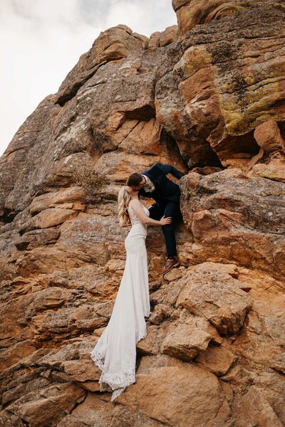 A bride and groom rock climbing together in rocky mountain national park in colorado