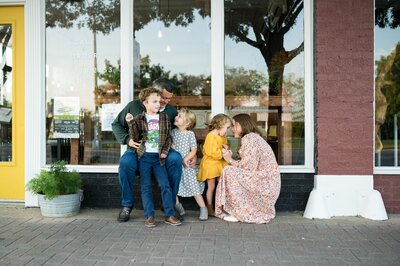 Mom holding newborn with siblings  sitting together