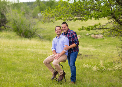 a couple sitting on a stool in a green grassy field