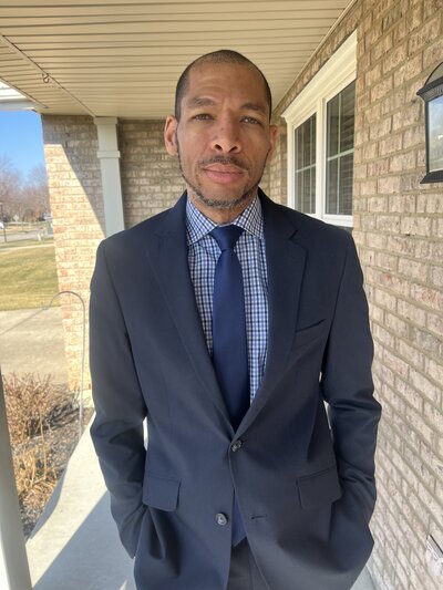 man in suit stands in front of building