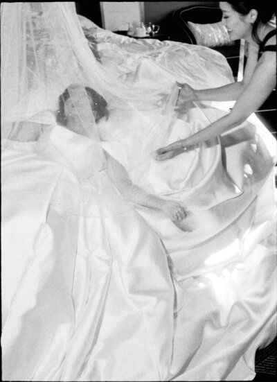 35mm film photo of bridesmaids helping bride into dress