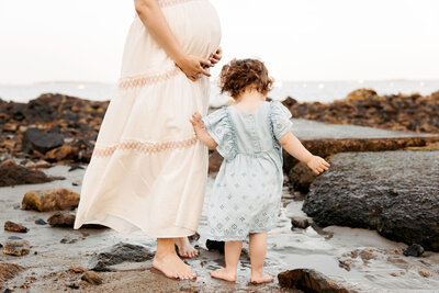 Expecting mother and her daughter at the beach in Massachusetts