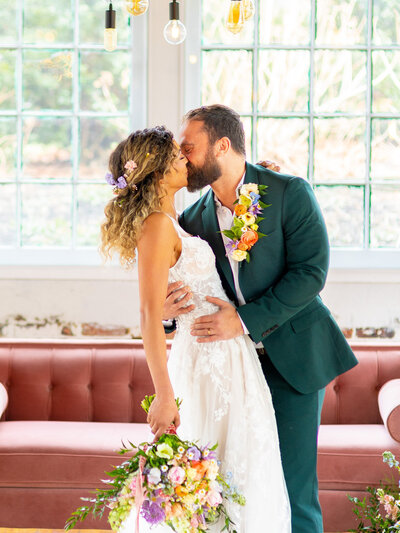 Bride and groom kissing with pink couch in the background