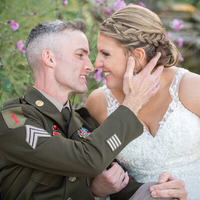 grooms holds brides face amongst flowers