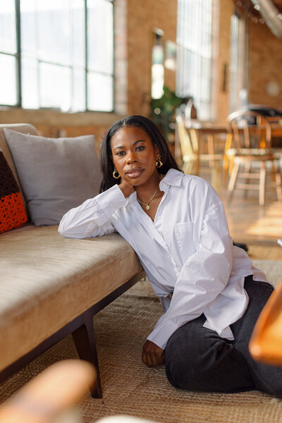 sex positive Chicago therapist leaning on a suede couch with her hand behind her head