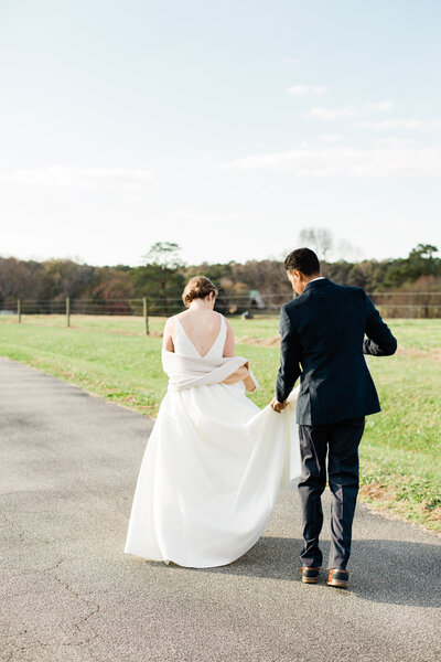Groom Helping Bride Carry Her Wedding Dress While They Walk Together