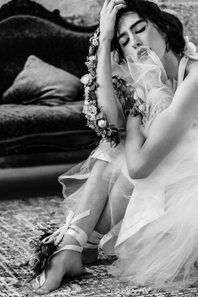 a luxurious black and white photo of a  woman in a tulle dress on the floor holding her knees