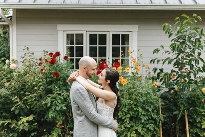 couple embracing in front of a window in a garden in Seattle.