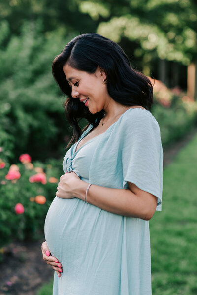 A pregnant mother holding her belly breathing in the moment in a blue dress, by northern VA photographer