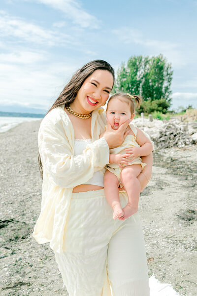 Family of 3 poses all together at the beach in Seattle