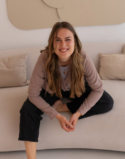 Patricia, Gründerin von ‚This Is For Me‘, sitzt auf einem Sofa und lächelt in die Kamera, Expertin für achtsame Ernährung und Körper-Mind-Balance.