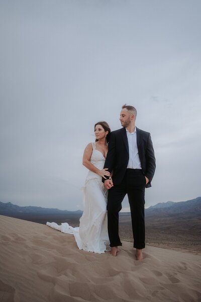 A wedding couple share a kiss in front of their hexagonal arch draped with fabric.