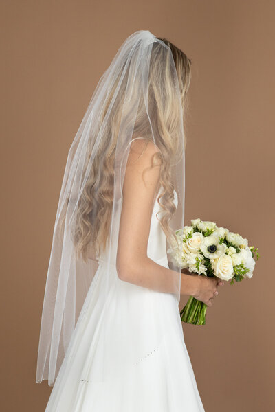 Bride wearing a fingertip length veil with crystal edge and holding a white and black bouquet