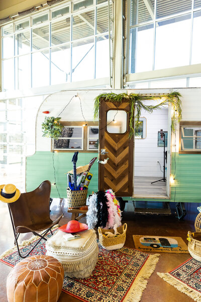 vintage small rv decorated boho style with lights and greenery with sitting area outside at the entrance to the rv