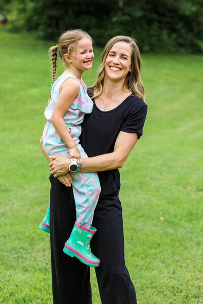 Mom holding daughter who is wearing rain boots | Family
