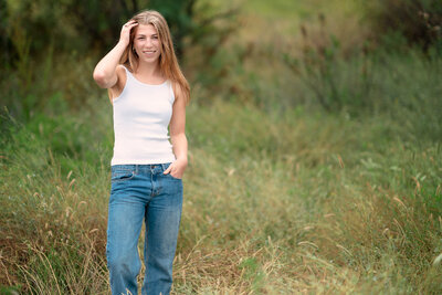 San Diego High school senior standing outdoors in a field of grass for her high school senior portraiat