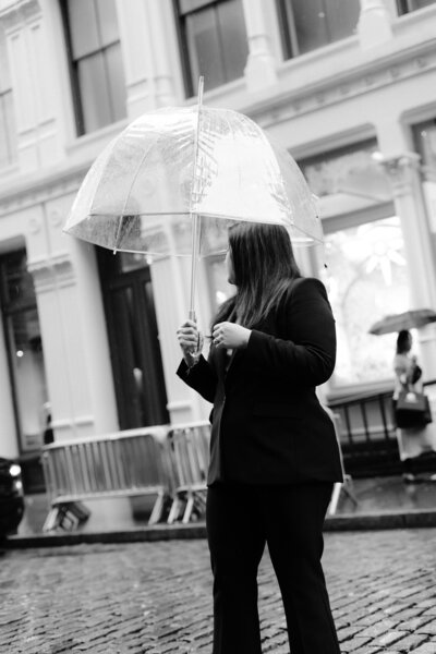 black and white image of a woman holding an umbrella looking away over her shoulder
