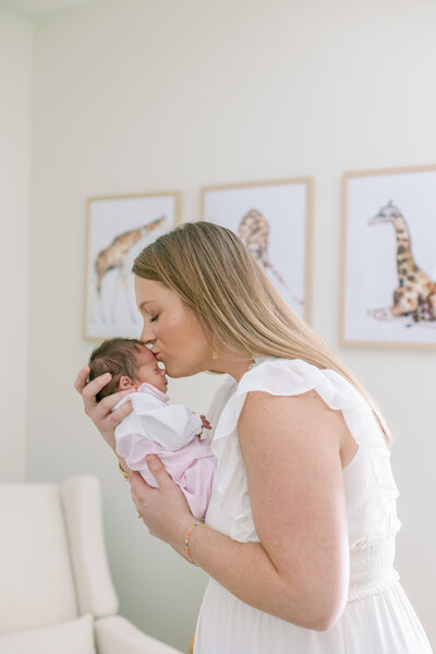 Mother kissing newborn baby in nursery