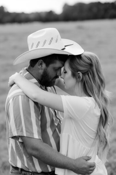 little rock ar engagement photographer captures man and woman embracing each other in a field  together