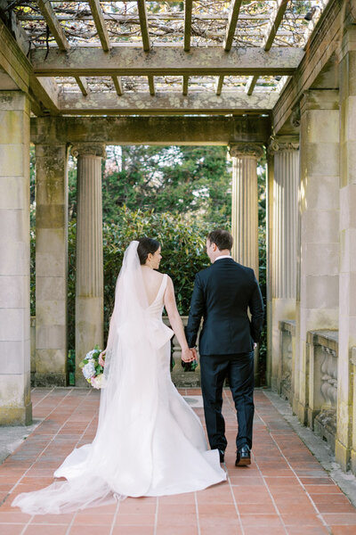 bride and groom walking away under trellis