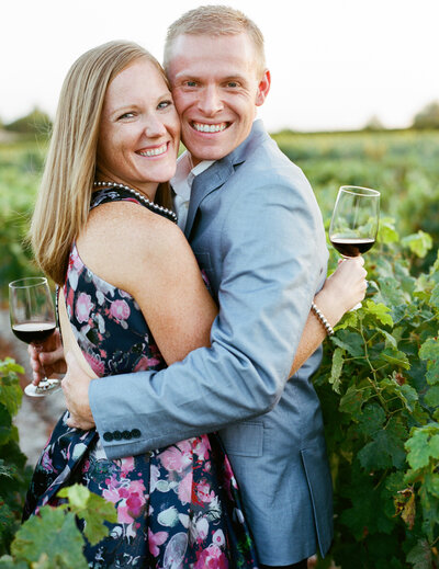 Couple Portrait looking camera in the French vineyard with glass of wine elegant