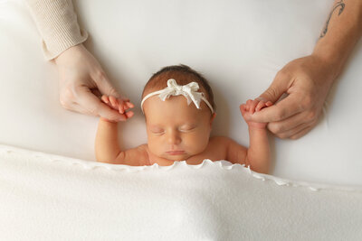 newborn baby girl holding mom and dasds hands