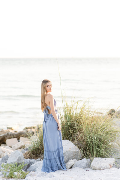 young woman standing on the beach in a blue dress